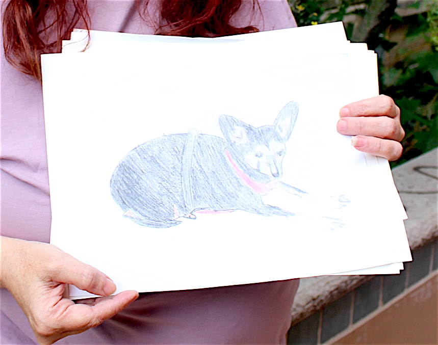 Sam, a resident at YWCA's Opportunity Place, holds a picture she made of a friend's pet. Sam says that creating art has built her confidence and helped her connect with community.